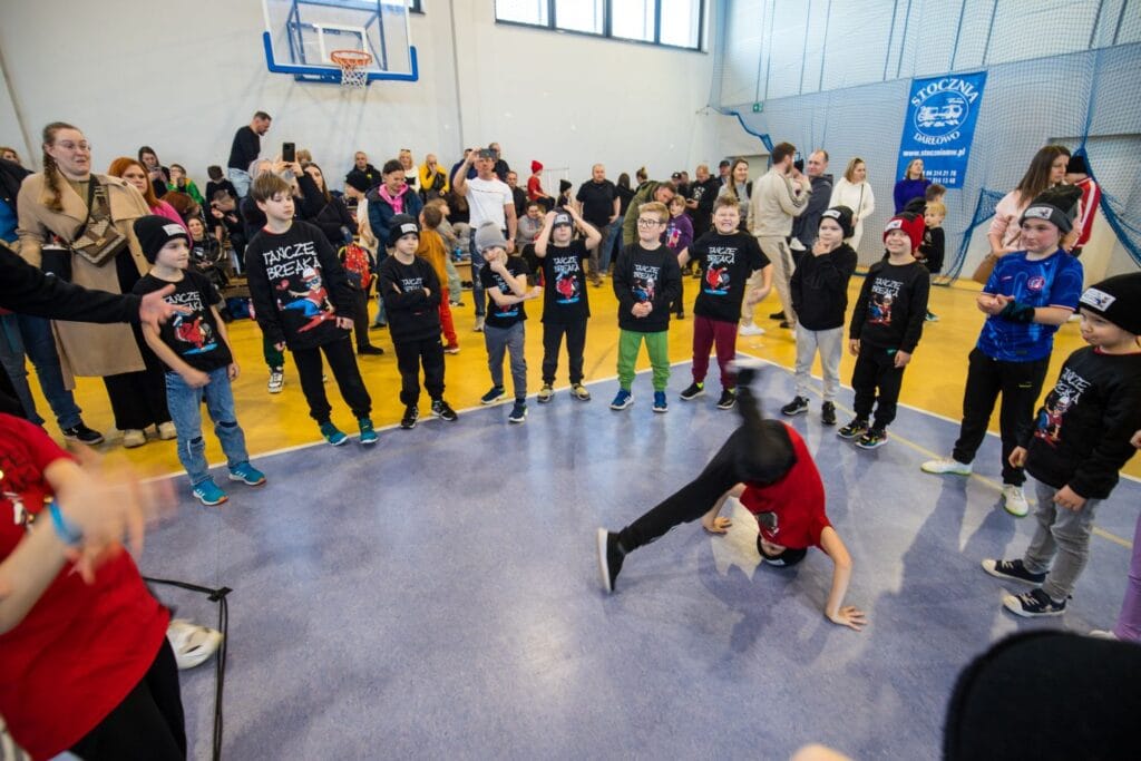 Dzieci uczestniczą w zawodach tanecznych w hali sportowej