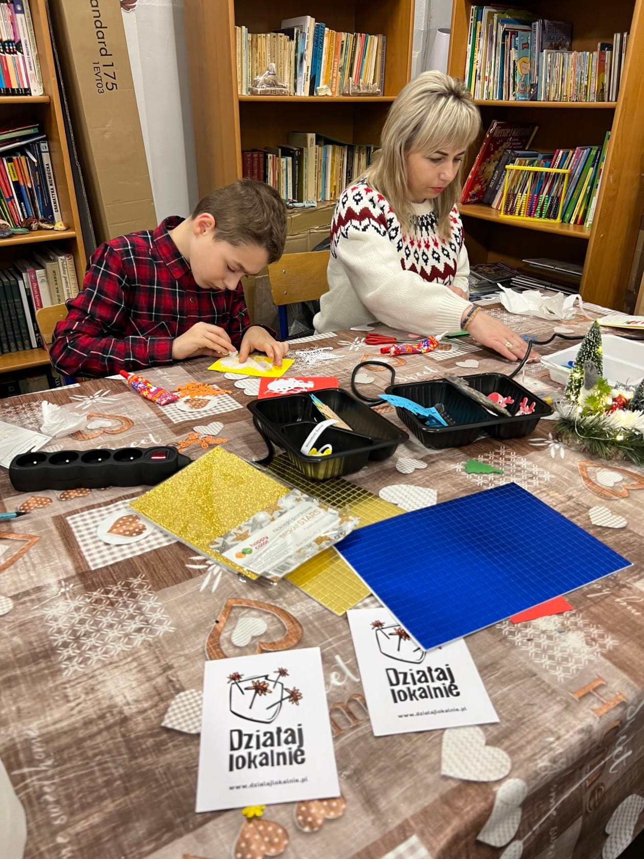 Dziecko i kobieta tworzą ozdoby w bibliotece